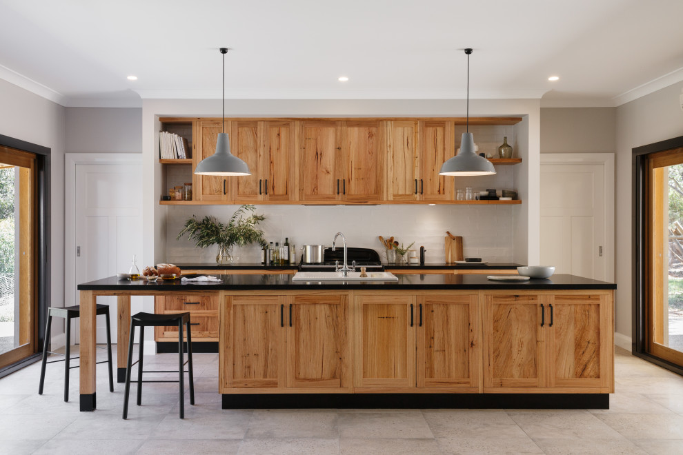 Inspiration for a transitional galley kitchen in Adelaide with stainless steel appliances, with island, a drop-in sink, shaker cabinets, medium wood cabinets, white splashback, subway tile splashback, grey floor and black benchtop.