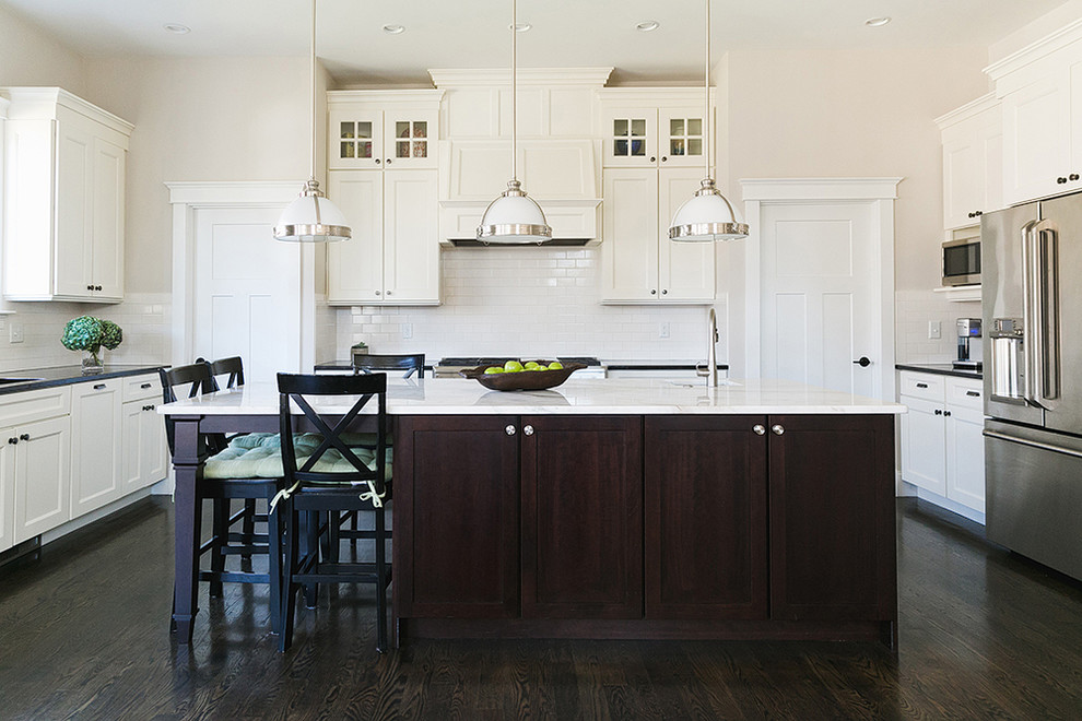Design ideas for a transitional u-shaped kitchen in Boston with recessed-panel cabinets, white cabinets, white splashback, subway tile splashback, stainless steel appliances, dark hardwood floors and with island.