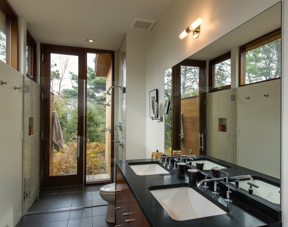 Mid-sized midcentury master bathroom in Boston with an undermount sink, flat-panel cabinets, medium wood cabinets, a freestanding tub, a curbless shower, beige tile, stone tile, porcelain floors, white walls, engineered quartz benchtops, black floor and a hinged shower door.