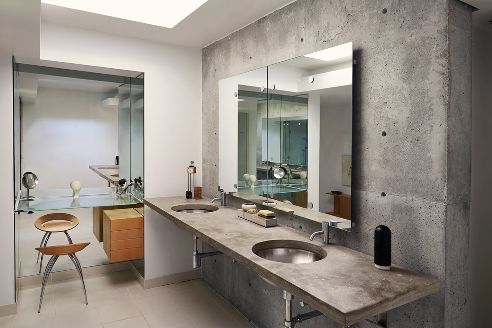 This is an example of a mid-sized industrial master bathroom in Other with open cabinets, a two-piece toilet, gray tile, cement tile, grey walls, ceramic floors, an undermount sink, concrete benchtops and beige floor.