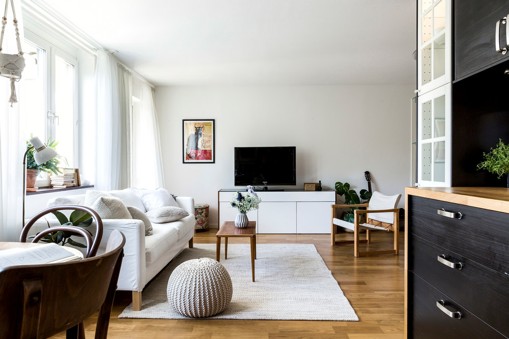 Design ideas for a mid-sized scandinavian formal open concept living room in Stockholm with white walls, medium hardwood floors, no fireplace and a freestanding tv.