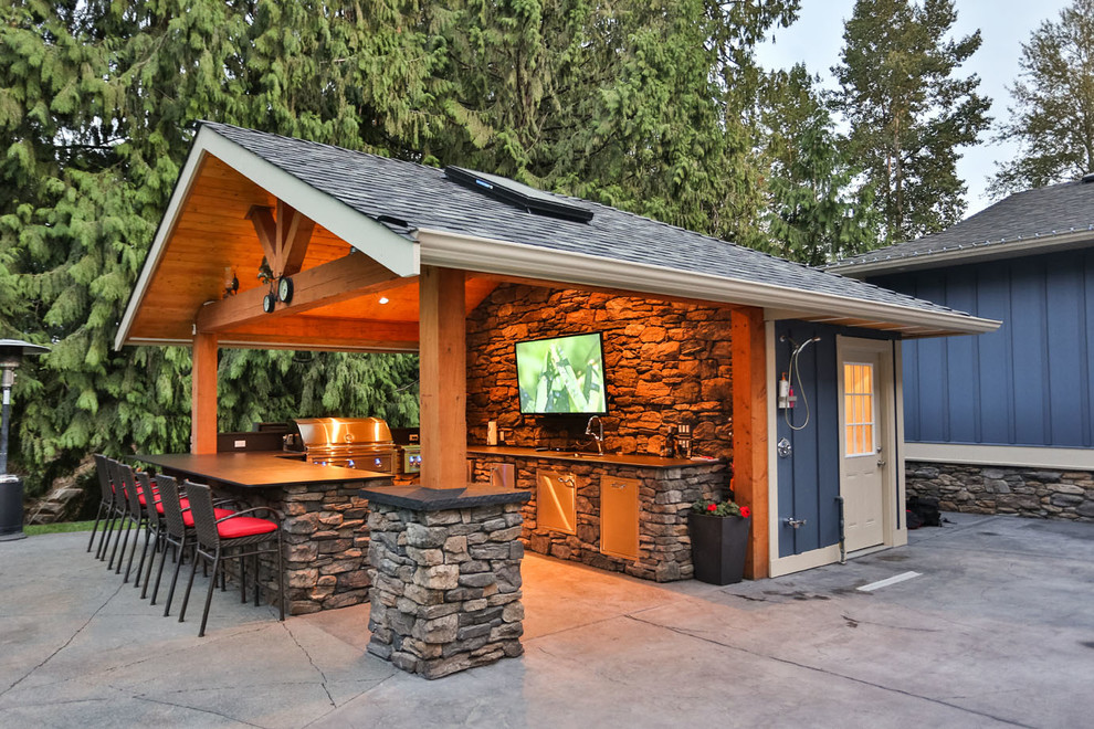 This is an example of an expansive arts and crafts backyard patio in Vancouver with an outdoor kitchen, concrete slab and a roof extension.