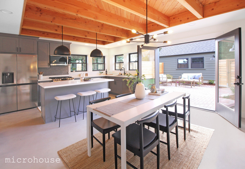 Esempio di una piccola sala da pranzo aperta verso la cucina stile americano con pareti bianche, pavimento grigio e travi a vista