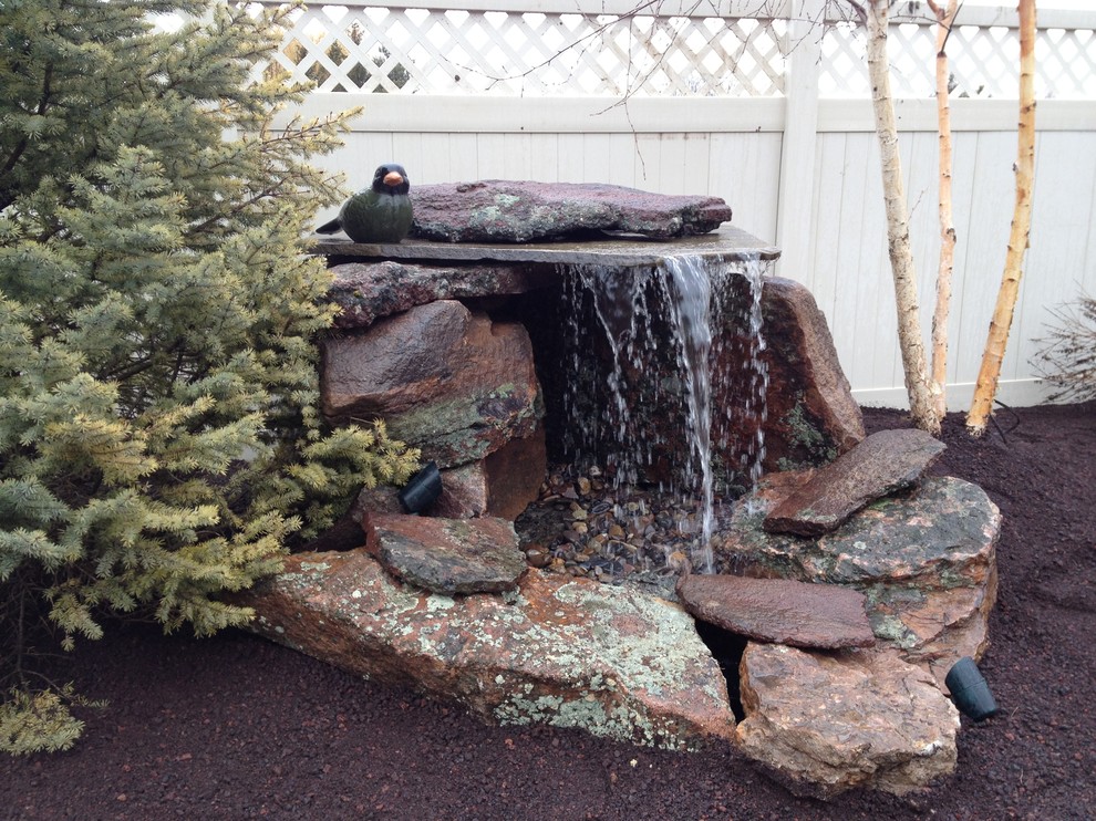 This is an example of a mid-sized country backyard partial sun garden for spring in Boise with a water feature and natural stone pavers.