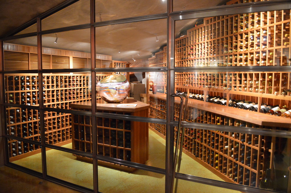 Large contemporary wine cellar in San Diego with concrete floors, storage racks and green floor.