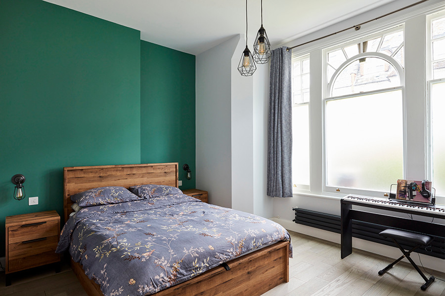 Foto de dormitorio principal industrial de tamaño medio con paredes verdes, suelo de madera en tonos medios y suelo gris