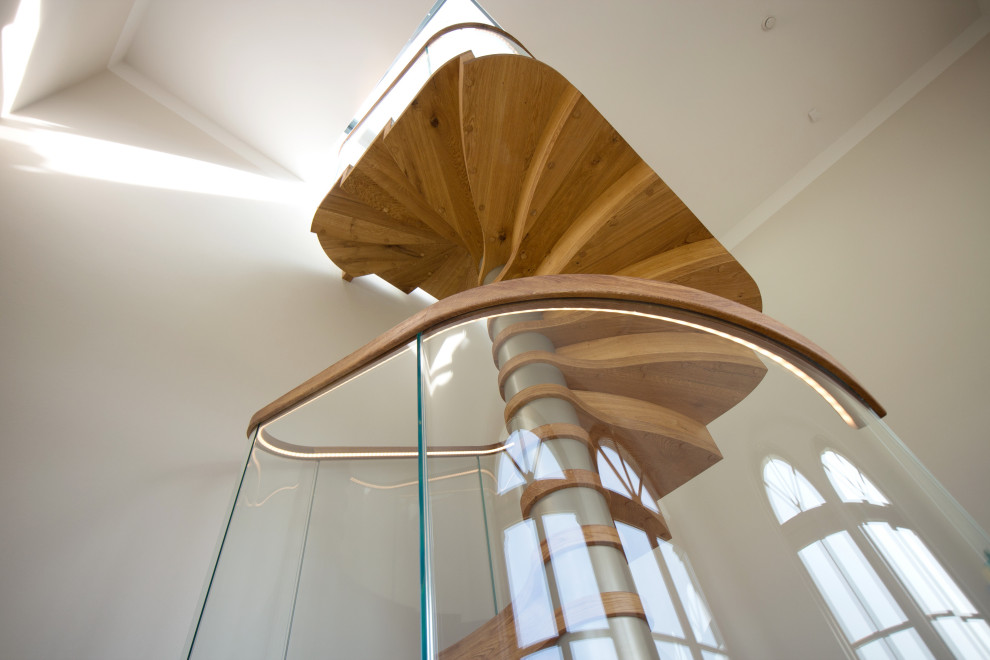 Cette image montre un grand escalier hélicoïdal design avec des marches en bois, des contremarches en bois, un garde-corps en verre et du papier peint.
