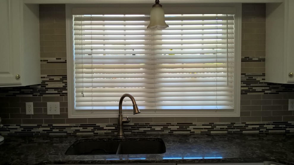Example of a transitional kitchen design with a double-bowl sink, raised-panel cabinets, white cabinets, granite countertops, multicolored backsplash, glass tile backsplash and stainless steel appliances