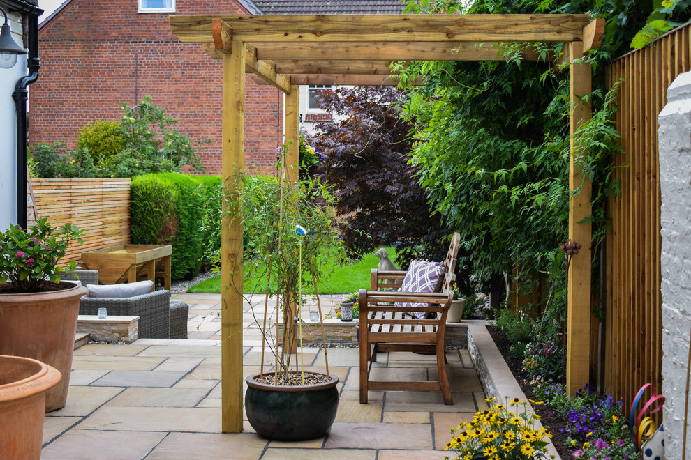 This is an example of a mid-sized traditional backyard patio in West Midlands with natural stone pavers.