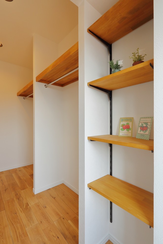 Идея дизайна: маленькая гардеробная комната унисекс с светлым паркетным полом и коричневым полом для на участке и в саду