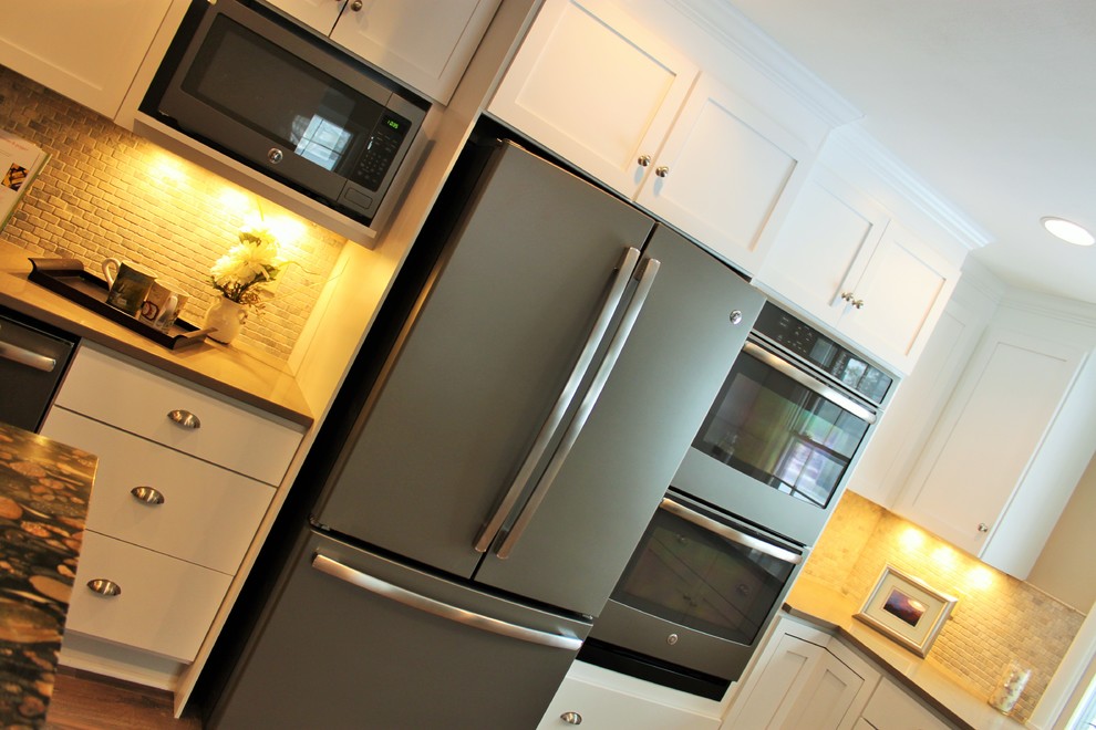 Example of a large transitional l-shaped medium tone wood floor eat-in kitchen design in Indianapolis with an undermount sink, shaker cabinets, white cabinets, quartz countertops, beige backsplash, stone tile backsplash and an island