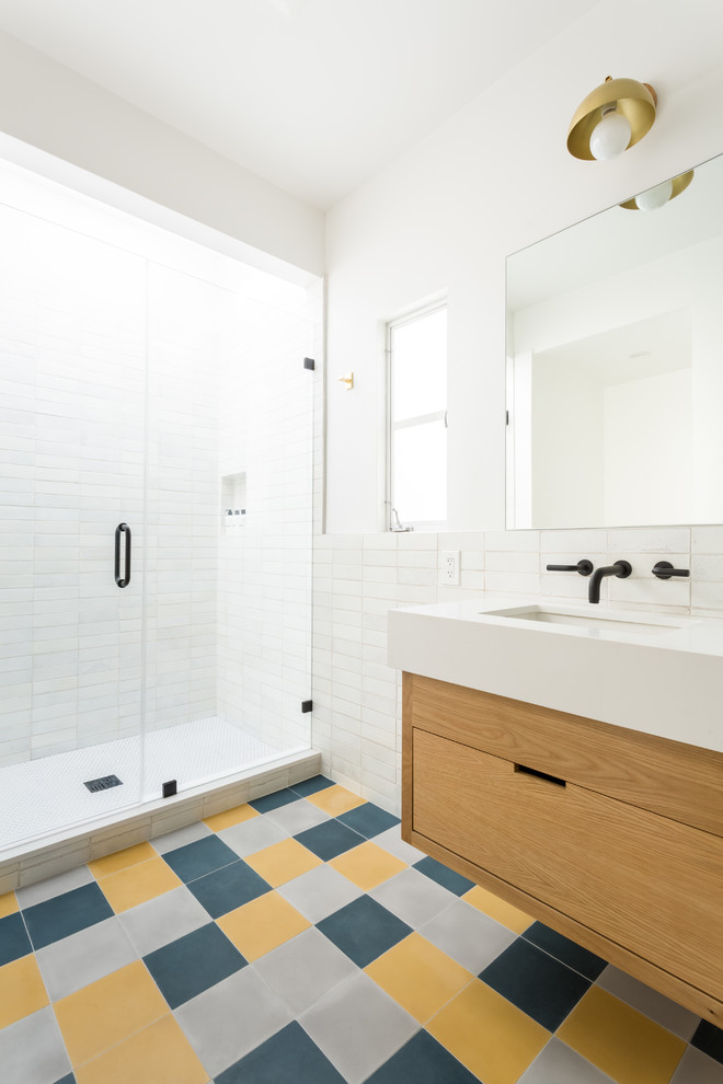 Design ideas for a mid-sized midcentury bathroom in Los Angeles with flat-panel cabinets, light wood cabinets, a drop-in tub, an alcove shower, a one-piece toilet, white tile, ceramic tile, white walls, cement tiles, an undermount sink, engineered quartz benchtops, a hinged shower door and white benchtops.