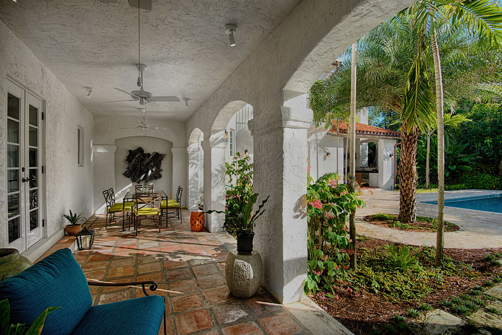 This is an example of a large mediterranean side yard verandah in Miami with natural stone pavers.