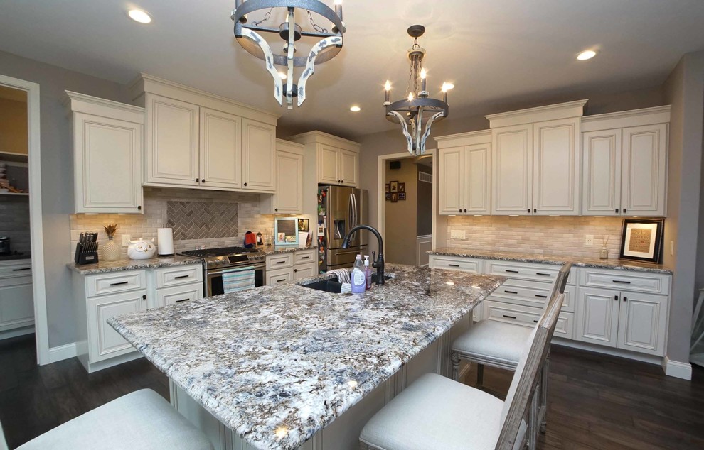 Example of a mid-sized transitional dark wood floor and brown floor open concept kitchen design in Chicago with a double-bowl sink, beaded inset cabinets, white cabinets, granite countertops, beige backsplash, subway tile backsplash, stainless steel appliances and an island