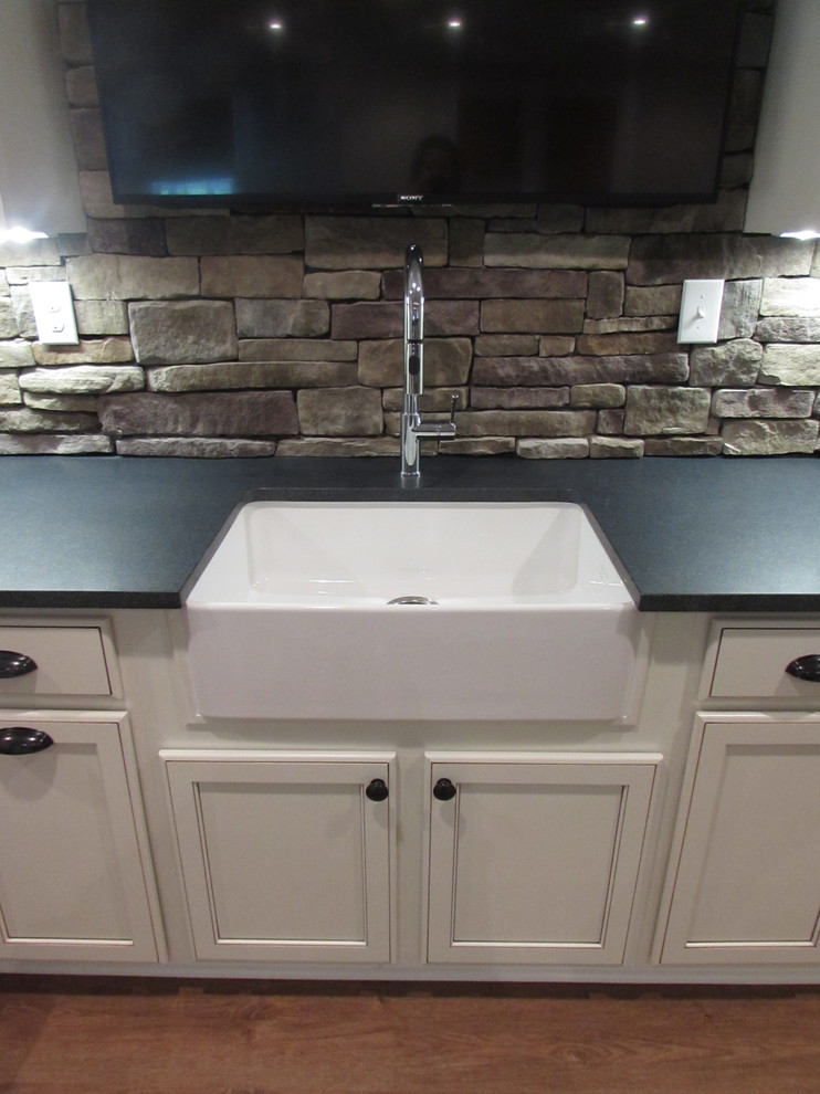 Example of a large walk-out vinyl floor basement design with beige walls, a standard fireplace and a stone fireplace