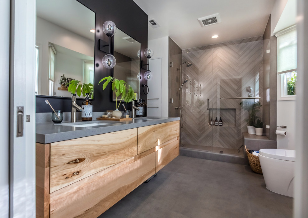This is an example of a mid-sized scandinavian master bathroom in Los Angeles with light wood cabinets, an alcove shower, a two-piece toilet, gray tile, porcelain tile, multi-coloured walls, porcelain floors, an undermount sink, engineered quartz benchtops, grey floor, a hinged shower door and flat-panel cabinets.