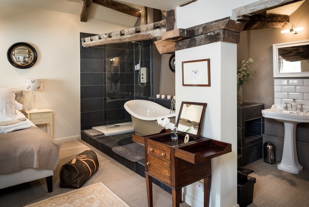 This is an example of a mid-sized contemporary master bathroom in Wiltshire with a freestanding tub, a shower/bathtub combo, a two-piece toilet, black tile, ceramic tile, beige walls, slate floors, a pedestal sink, tile benchtops and grey floor.