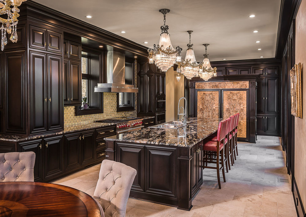 Photo of an expansive traditional open plan kitchen in Milwaukee with a triple-bowl sink, raised-panel cabinets, dark wood cabinets, granite benchtops, metallic splashback, glass tile splashback, panelled appliances, limestone floors, with island and beige floor.