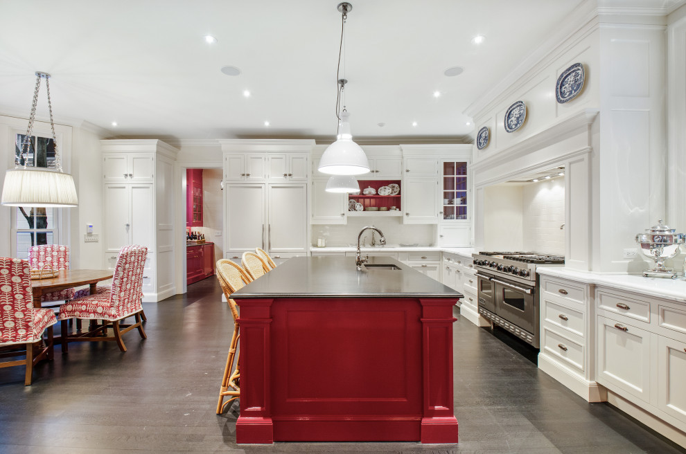 Photo of a traditional l-shaped eat-in kitchen in Chicago with an undermount sink, recessed-panel cabinets, white cabinets, white splashback, stainless steel appliances, with island, grey floor and white benchtop.