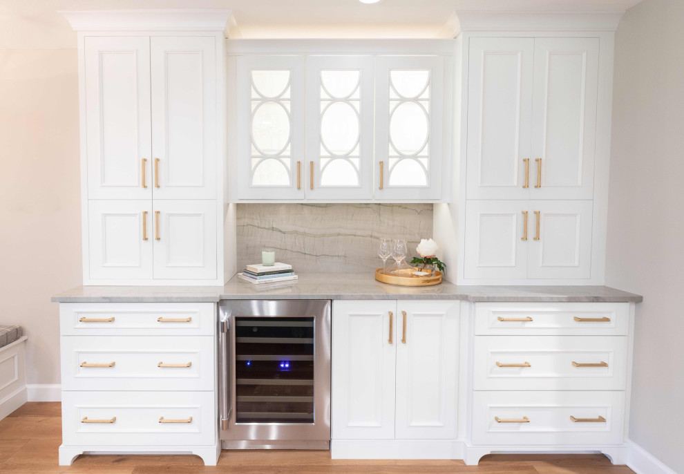 Inredning av ett klassiskt mellanstort grå grått kök, med en rustik diskho, luckor med infälld panel, vita skåp, bänkskiva i kvartsit, grått stänkskydd, rostfria vitvaror, mellanmörkt trägolv, en köksö och brunt golv