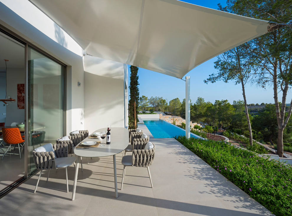Photo of a mid-sized modern backyard verandah in Alicante-Costa Blanca with an awning.
