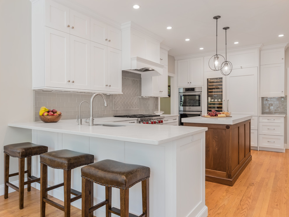 Transitional u-shaped eat-in kitchen photo in Providence with an undermount sink, white cabinets, quartzite countertops, glass tile backsplash, stainless steel appliances and an island