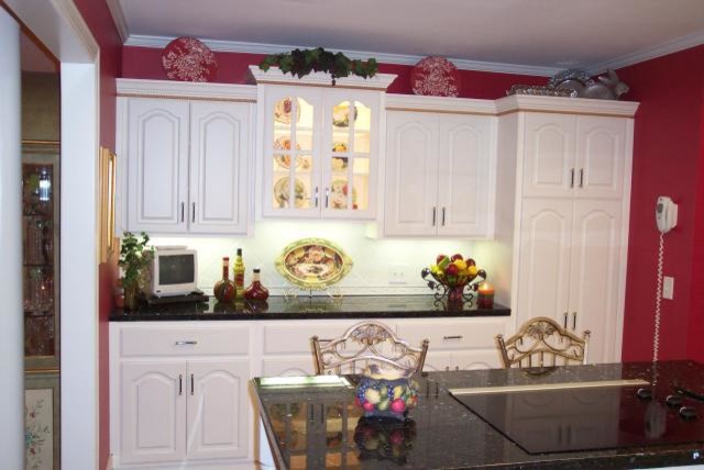 Example of a mid-sized single-wall eat-in kitchen design with white cabinets, granite countertops and an island