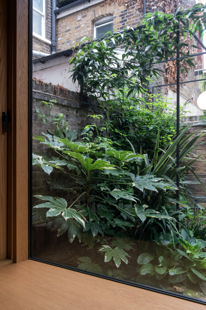 Foto di un piccolo giardino minimal in ombra dietro casa con pavimentazioni in mattoni e recinzione in pietra