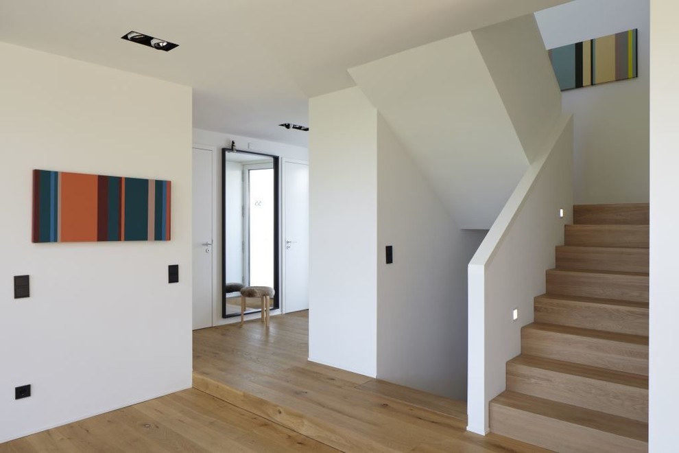Photo of a contemporary entry hall in Cologne with white walls and medium hardwood floors.
