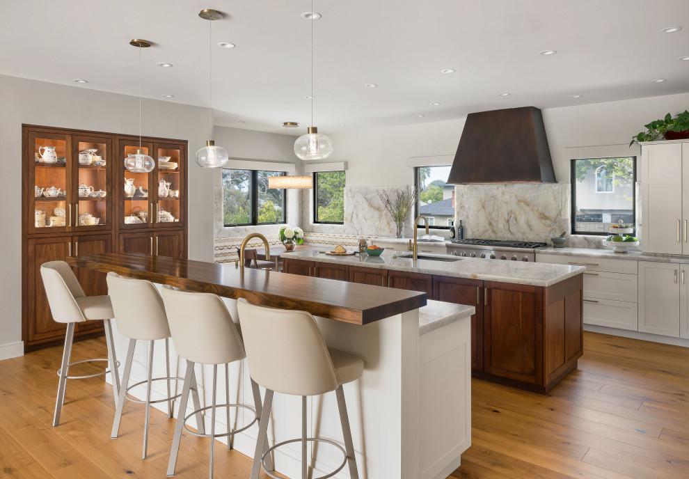 Design ideas for a large transitional open plan kitchen in San Diego with an undermount sink, recessed-panel cabinets, white cabinets, quartzite benchtops, white splashback, stone slab splashback, stainless steel appliances, medium hardwood floors, multiple islands and white benchtop.