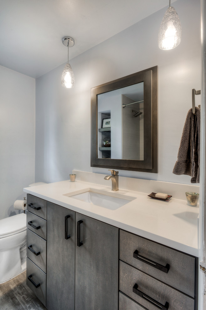 Design ideas for a mid-sized transitional master bathroom in Seattle with recessed-panel cabinets, white cabinets, an undermount tub, a shower/bathtub combo, a one-piece toilet, white tile, blue walls, concrete floors, an undermount sink and quartzite benchtops.
