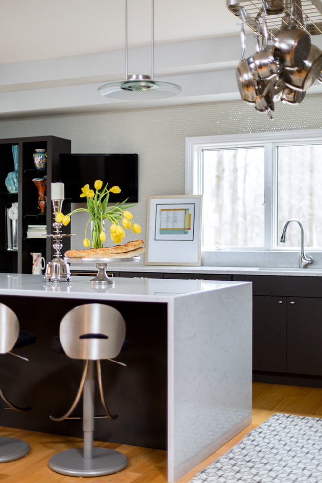 Large transitional l-shaped light wood floor kitchen photo with flat-panel cabinets, dark wood cabinets, gray backsplash, stainless steel appliances and an island