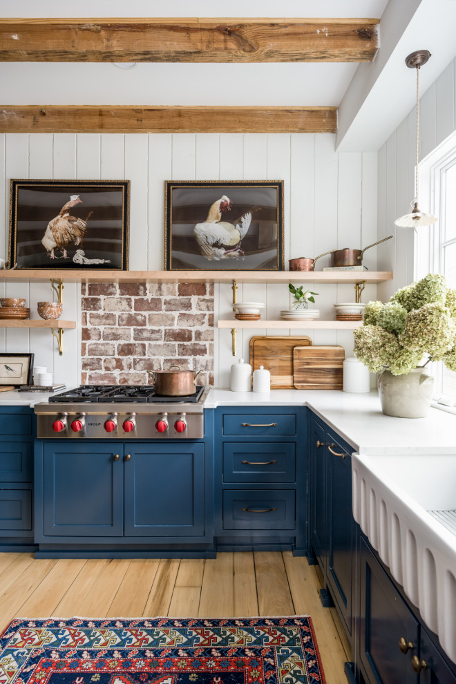 Inspiration for a medium sized farmhouse u-shaped enclosed kitchen in Nashville with a belfast sink, beaded cabinets, blue cabinets, engineered stone countertops, white splashback, wood splashback, stainless steel appliances, light hardwood flooring, an island, yellow floors, white worktops and exposed beams.