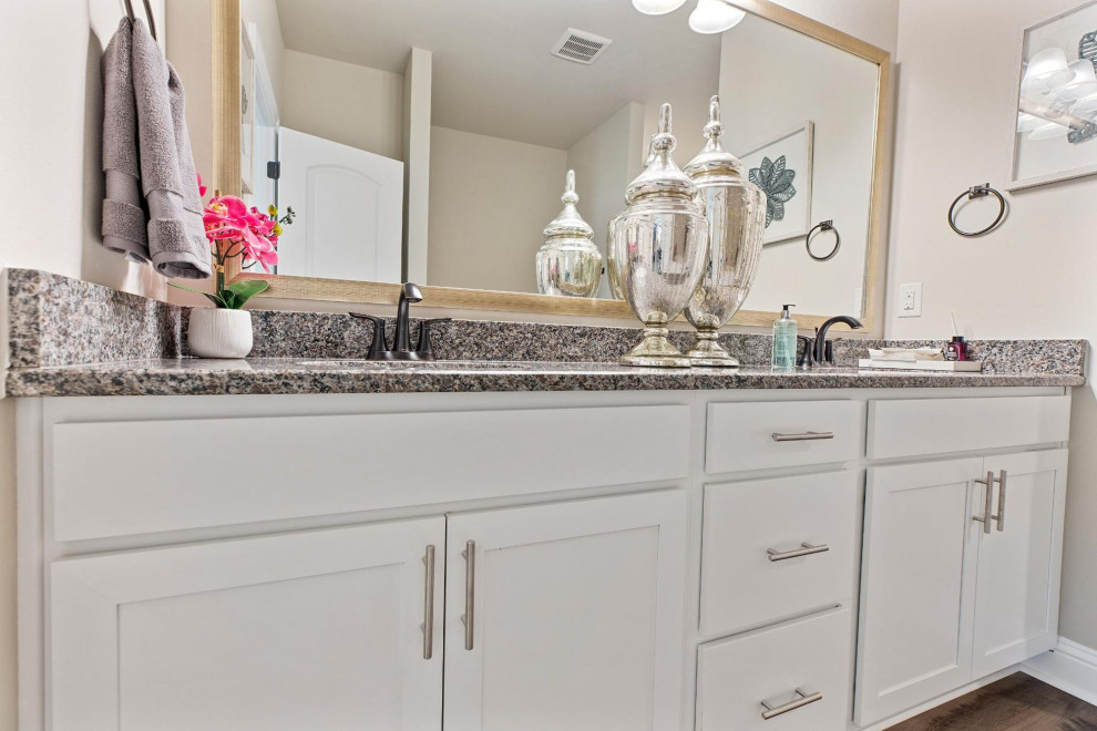 Inspiration for a mid-sized traditional master bathroom in Other with white cabinets, grey walls, medium hardwood floors, granite benchtops, brown floor, grey benchtops, a double vanity and a built-in vanity.