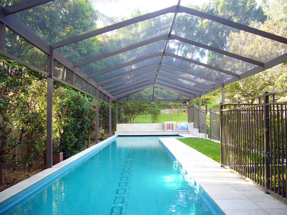 Photo of a mid-sized contemporary backyard pool in Other with a pool house and tile.