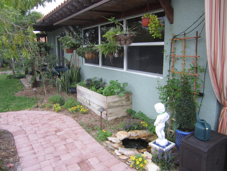 This is an example of a large tropical backyard garden in Miami with a container garden and brick pavers.