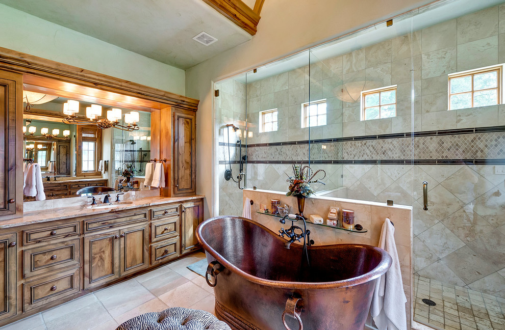 This is an example of an expansive mediterranean master bathroom in Dallas with beaded inset cabinets, dark wood cabinets, a freestanding tub, a double shower, beige tile, beige walls, travertine floors, an undermount sink, brown floor, a hinged shower door and beige benchtops.