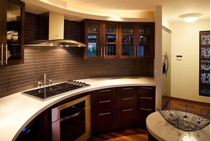 Inspiration for a mid-sized asian kitchen in Hawaii with dark wood cabinets, solid surface benchtops, brown splashback, matchstick tile splashback, stainless steel appliances, dark hardwood floors, with island and brown floor.