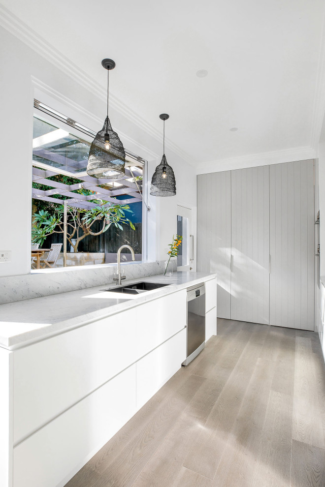 Design ideas for a mid-sized contemporary single-wall kitchen pantry in Sydney with a drop-in sink, shaker cabinets, beige cabinets, marble benchtops, grey splashback, marble splashback, stainless steel appliances, light hardwood floors, with island, beige floor and grey benchtop.