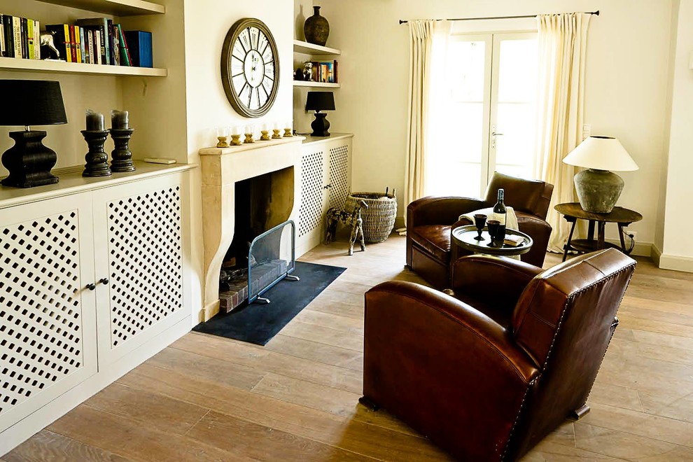 Mittelgroßes, Repräsentatives, Fernseherloses Mediterranes Wohnzimmer mit gelber Wandfarbe, braunem Holzboden, Kamin und Kaminumrandung aus Stein in Hamburg