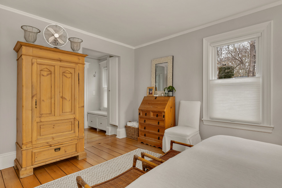 Cette image montre une chambre d'amis rustique de taille moyenne avec un mur gris, parquet clair, aucune cheminée et un sol marron.