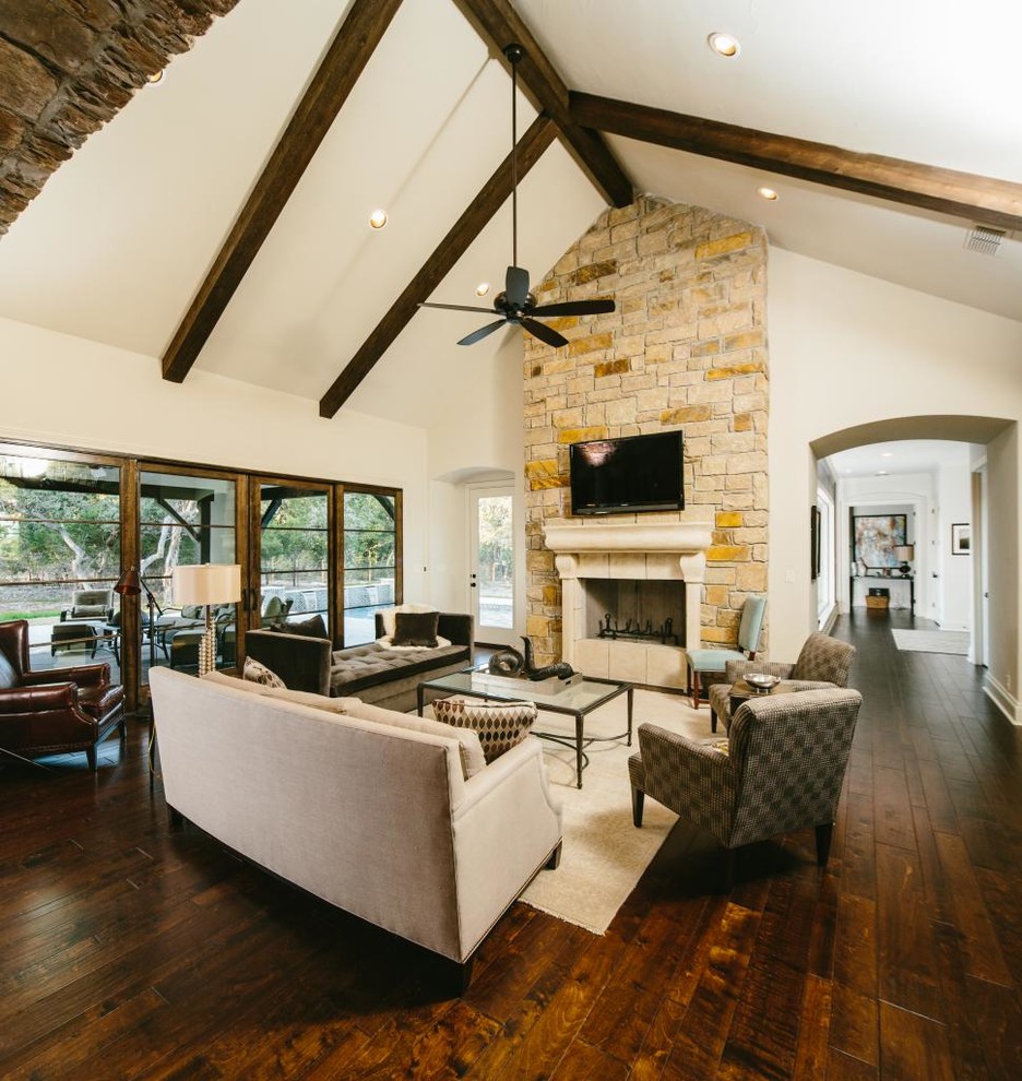 Photo of a traditional open concept living room in Austin with white walls, dark hardwood floors, a standard fireplace, a stone fireplace surround and a wall-mounted tv.