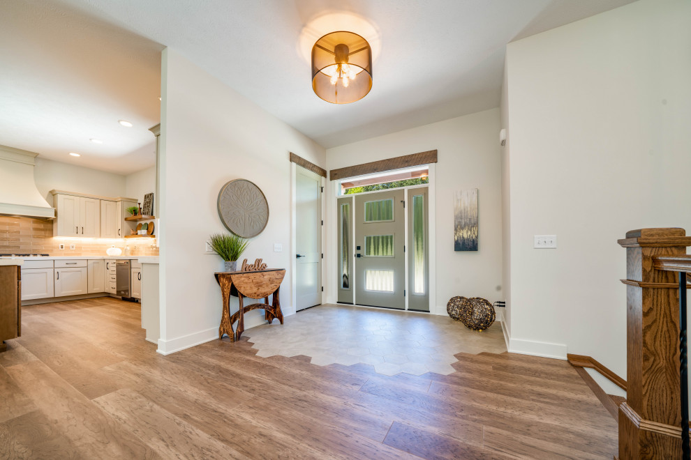 Example of a large eclectic light wood floor, brown floor and exposed beam entryway design in Grand Rapids with white walls and a gray front door