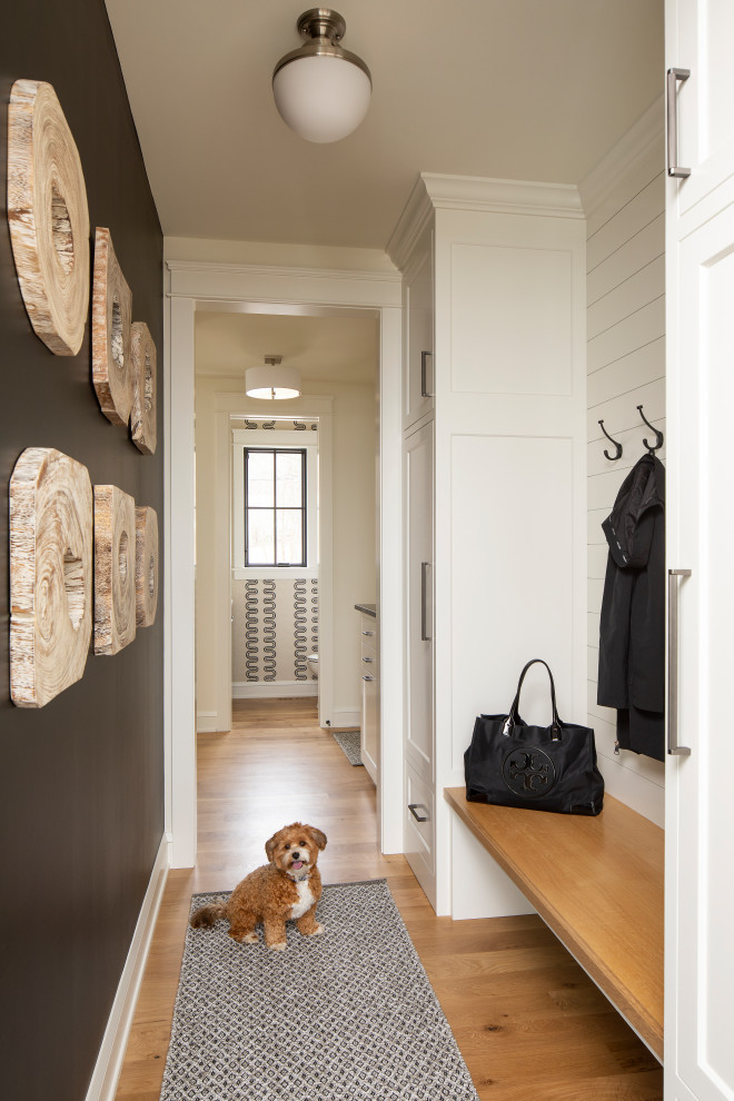Inspiration for a beach style mudroom in Minneapolis with black walls, light hardwood floors and planked wall panelling.