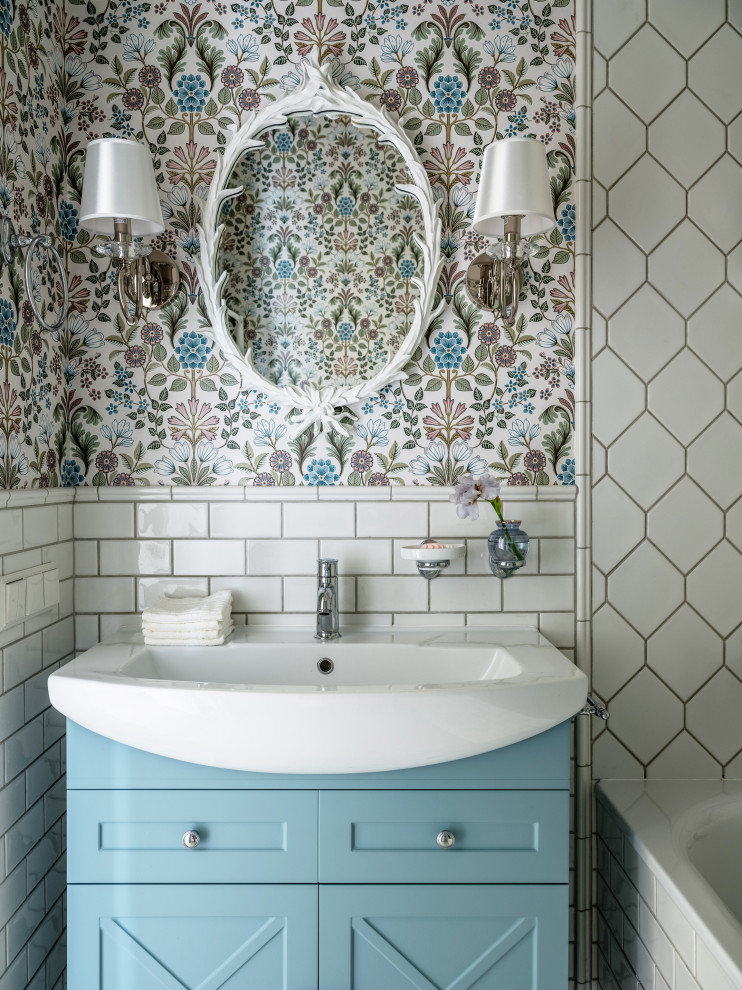 Design ideas for a mid-sized country bathroom in Moscow with recessed-panel cabinets, blue cabinets, white tile, ceramic tile, multi-coloured walls, porcelain floors, a drop-in sink, white benchtops, an enclosed toilet, a single vanity, a freestanding vanity, wallpaper and an alcove tub.