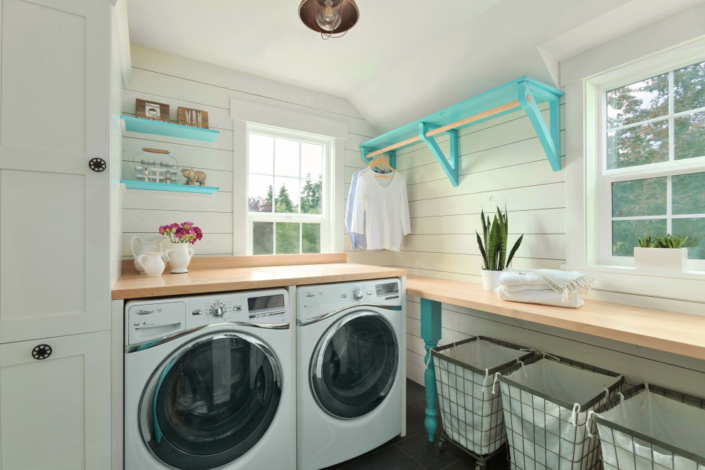 Mid-sized country l-shaped dedicated laundry room in Seattle with shaker cabinets, white cabinets, wood benchtops, shiplap splashback, white walls, porcelain floors, a side-by-side washer and dryer, black floor, brown benchtop and planked wall panelling.