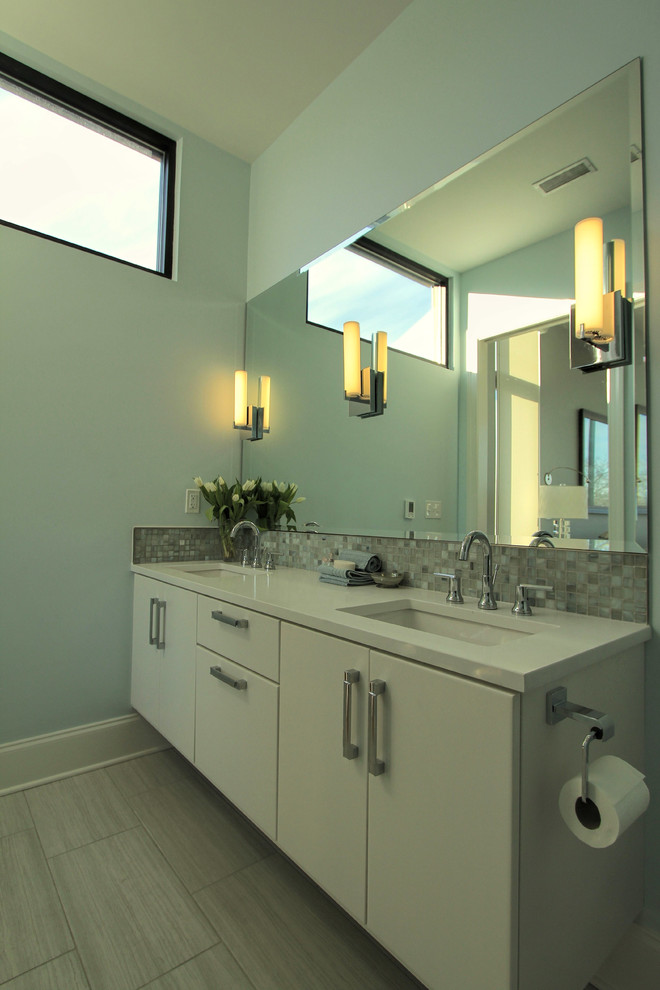 Inspiration for a mid-sized modern master bathroom in Nashville with flat-panel cabinets, white cabinets, a two-piece toilet, glass tile, grey walls, ceramic floors, an undermount sink, solid surface benchtops and a curbless shower.