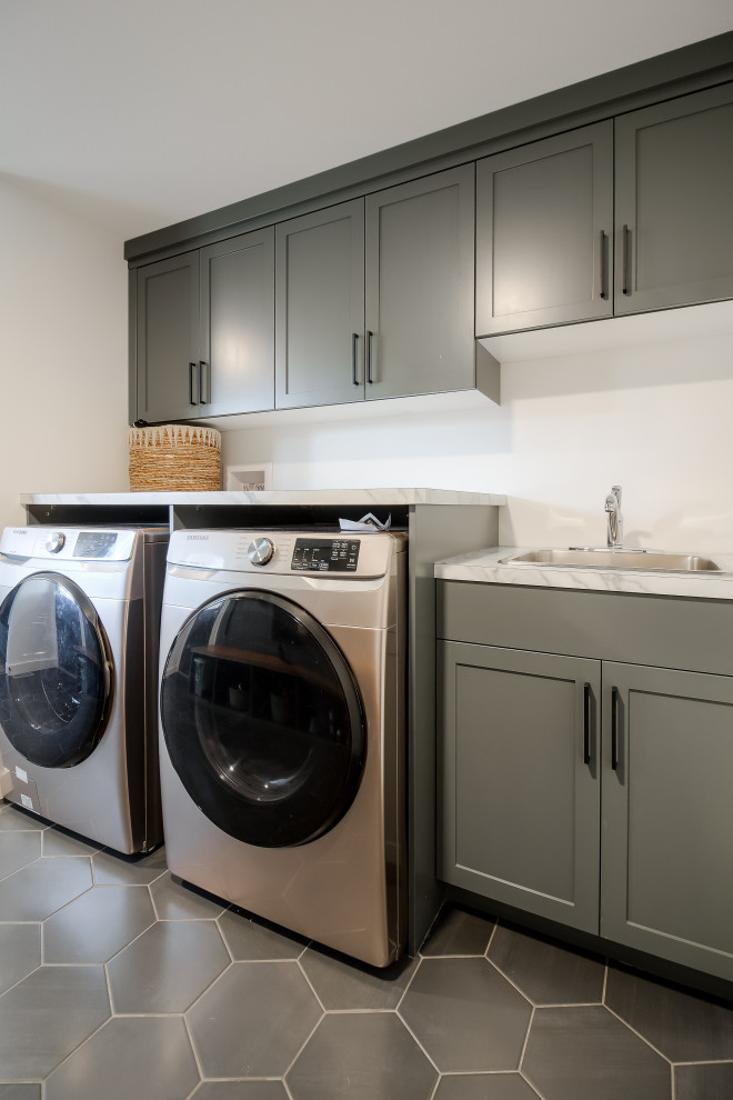 Photo of a medium sized midcentury galley utility room in Calgary with a built-in sink, shaker cabinets, green cabinets, quartz worktops, white walls, ceramic flooring, a side by side washer and dryer, grey floors and white worktops.