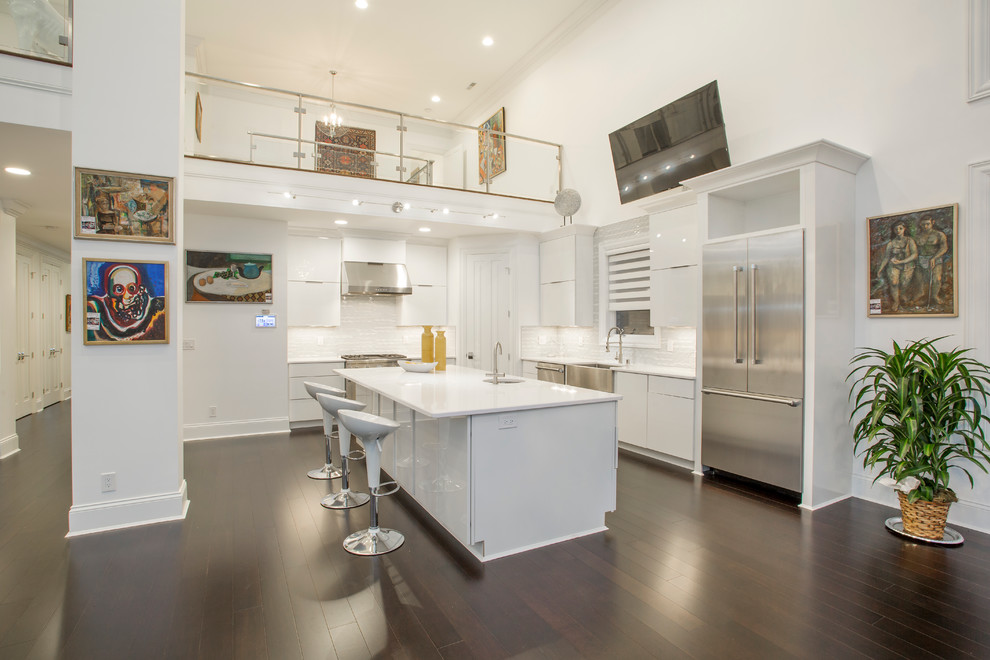 This is an example of a large contemporary eat-in kitchen in Cincinnati with a farmhouse sink, white cabinets, glass tile splashback, bamboo floors and with island.