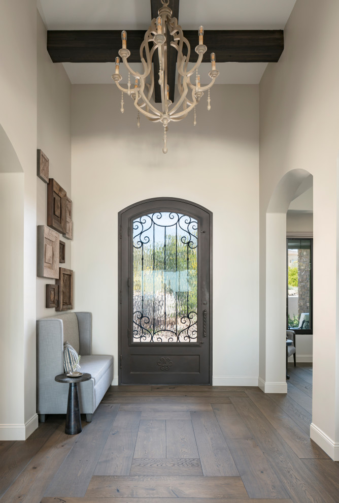 На фото: огромное фойе в стиле неоклассика (современная классика) с серыми стенами, темным паркетным полом, одностворчатой входной дверью, коричневой входной дверью, коричневым полом и балками на потолке